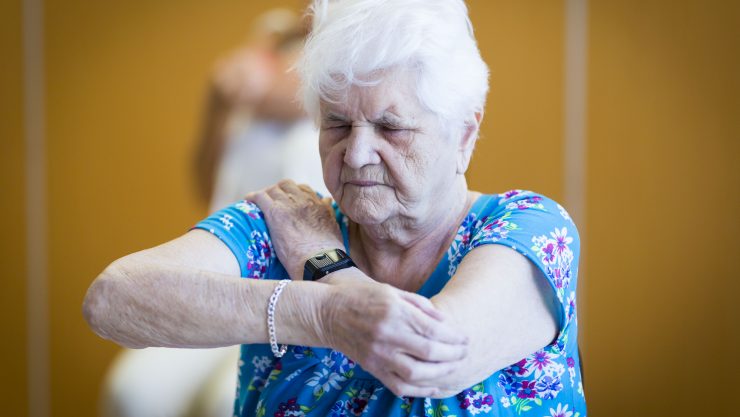 Image shows an elderly lady stretching her arms.