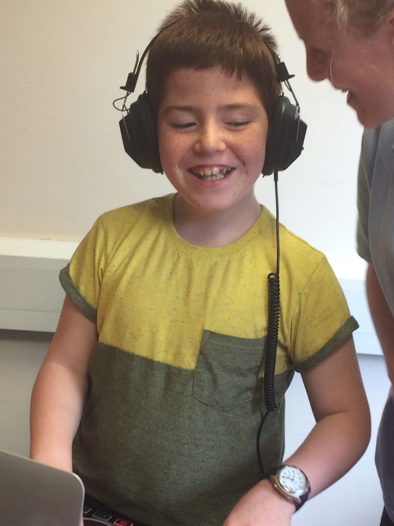 Image shows a young boy wearing headphones and listening to music.