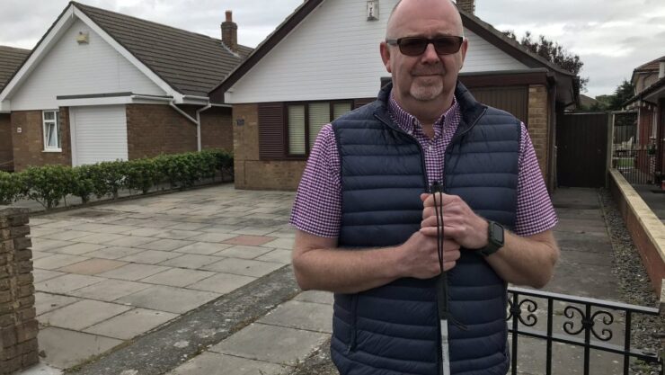 Man stood outside house with cane