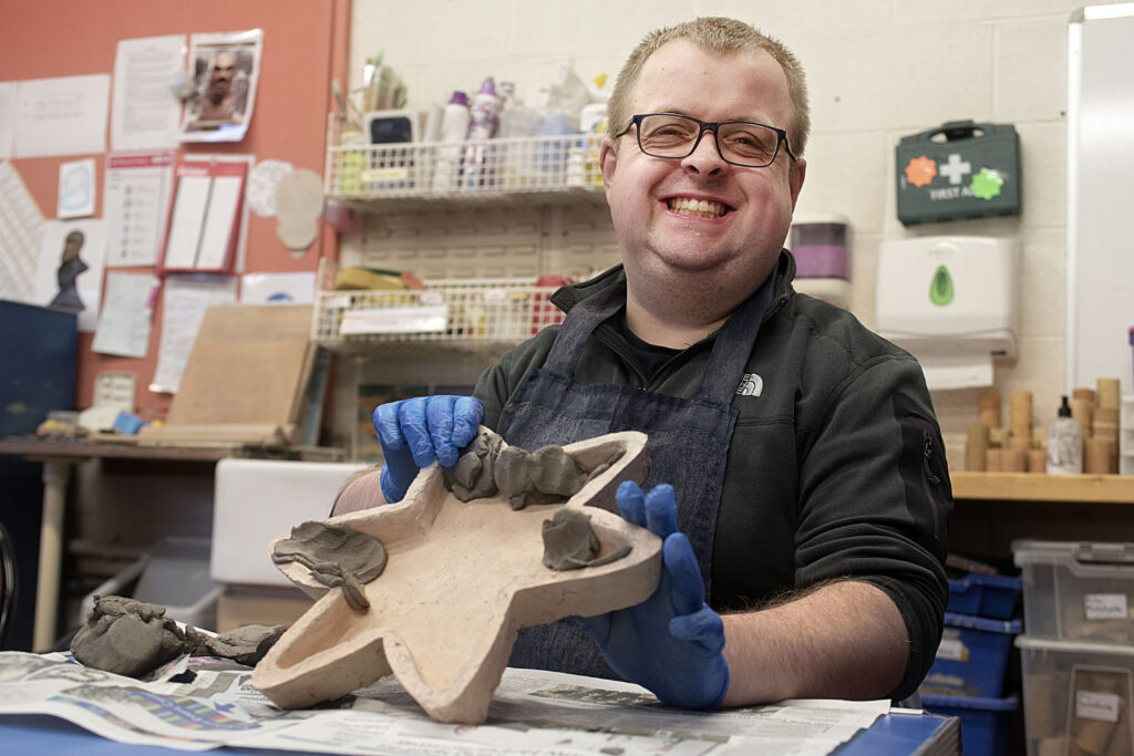 Art maker holding up a piece created in pottery