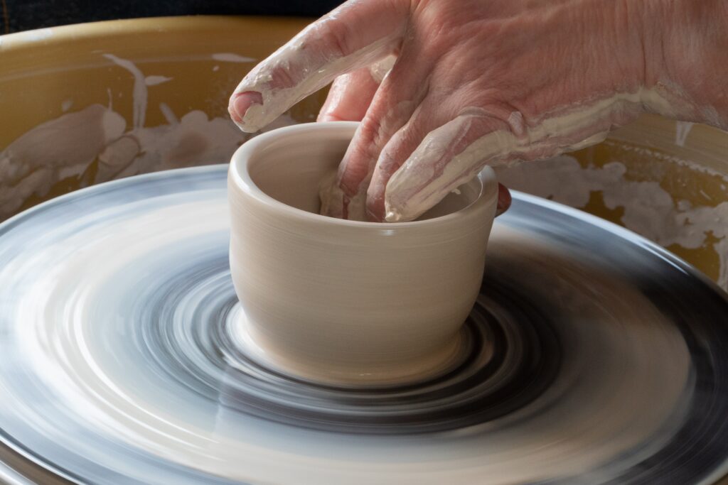 Potters wheel with someone shaping clay into a bowl