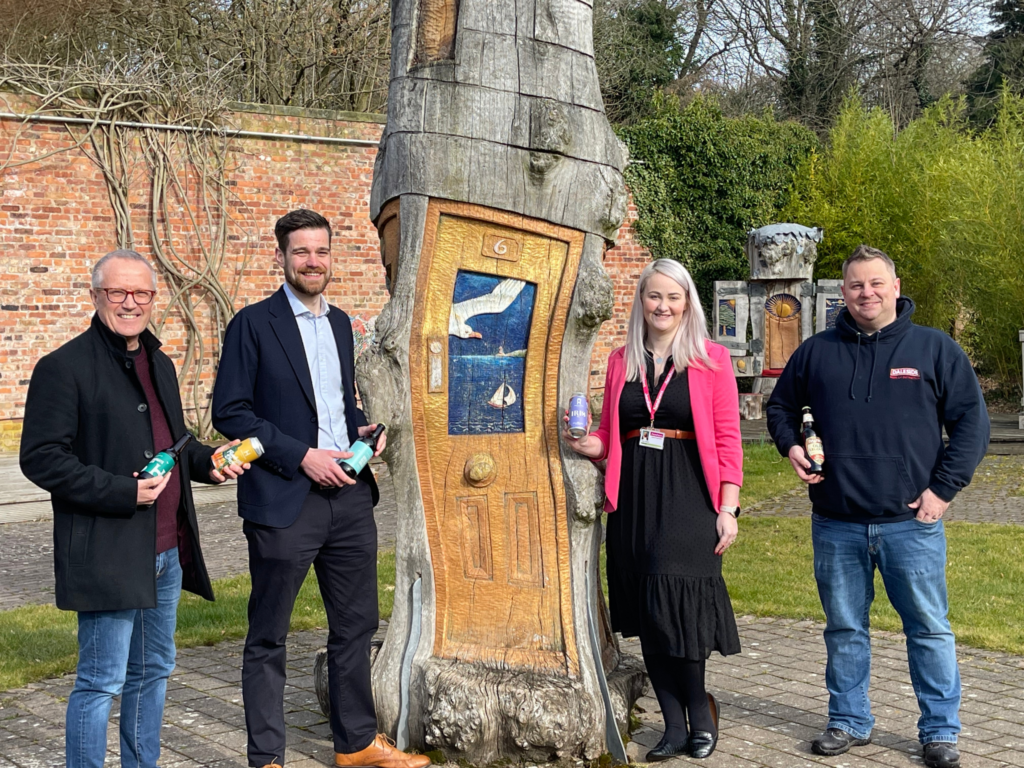 Henshaws team and sponsors stood next to a tree sculpture at our Arts and Crafts Centre