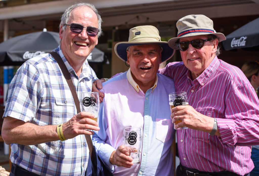 Attendees of the beer festival smiling at the camera with pint glasses in their hands
