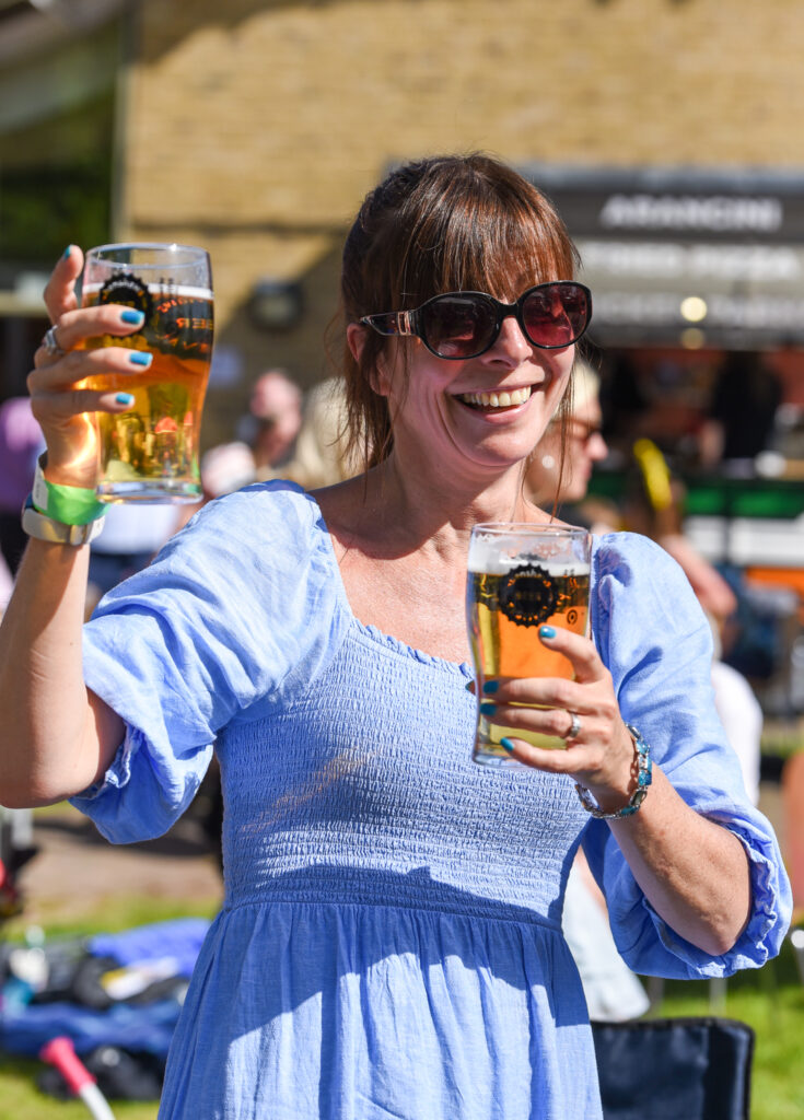 An attendee at the festival holding pint glasses with beer in.