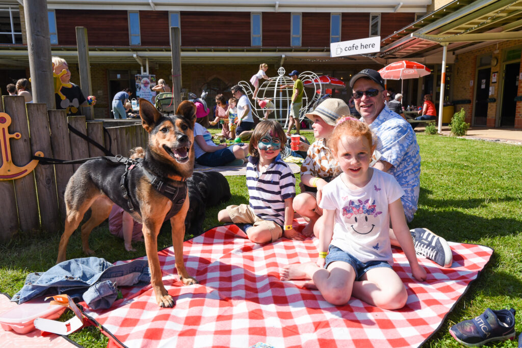 Family and their dog at the beer festival, sat on a picnic blanket in the sunshine