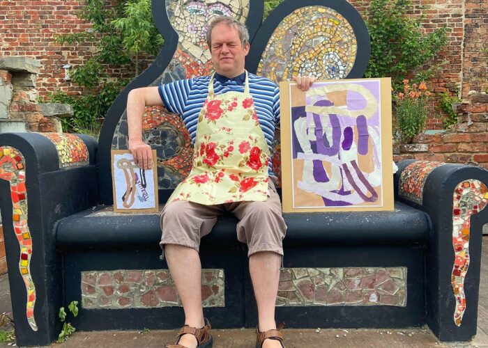 Art maker Andrew sat on a beautiful mosaic bench holding pieces of art he has made