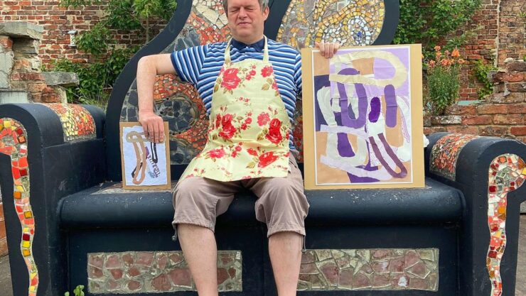 Art maker Andrew sat on a beautiful mosaic bench holding pieces of art he has made
