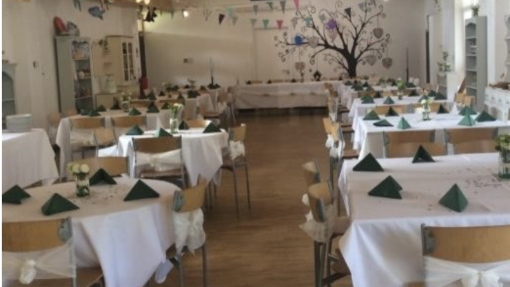 Tables are set with table clothes and napkins for an event in our cafe